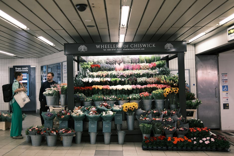 A floral arrangement display at Wheeler of Chiswick in an underground station, featuring a variety of fresh flowers arranged in buckets and wrapping, including roses, tulips, daisies, and chrysanthemu